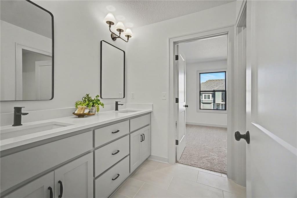 Bathroom with a white double-sink vanity, black faucets, and mirrors beside an open doorway.