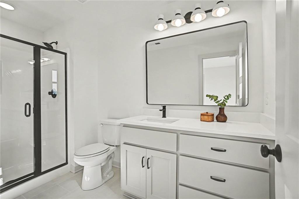 Bathroom with a white vanity, black fixtures, and a glass shower with black framing.