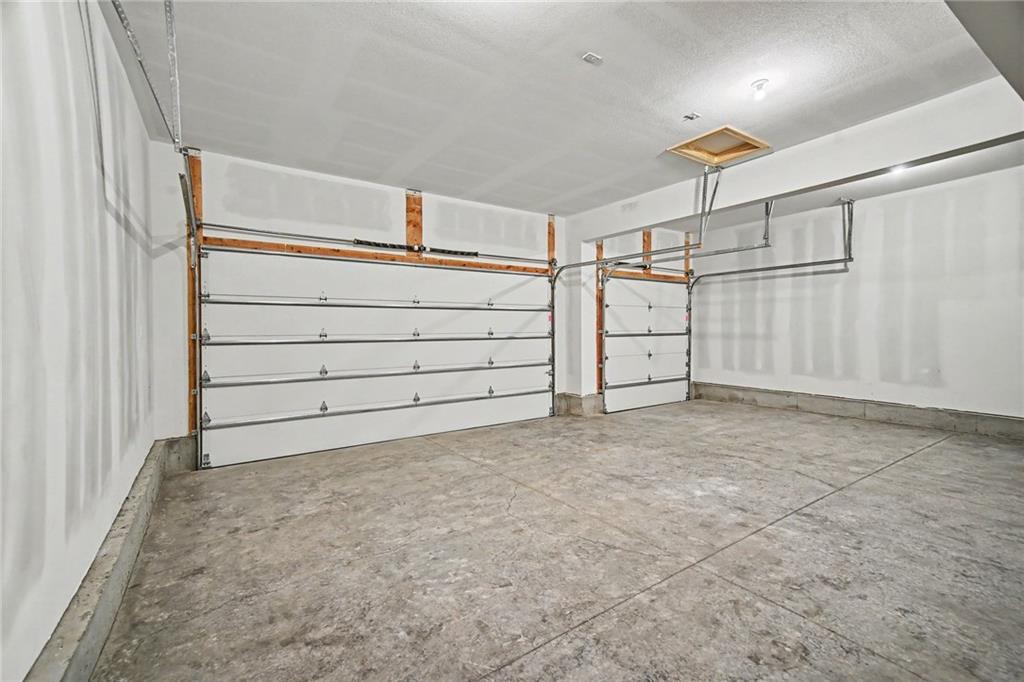 Empty garage with two white overhead doors and a bare concrete floor.