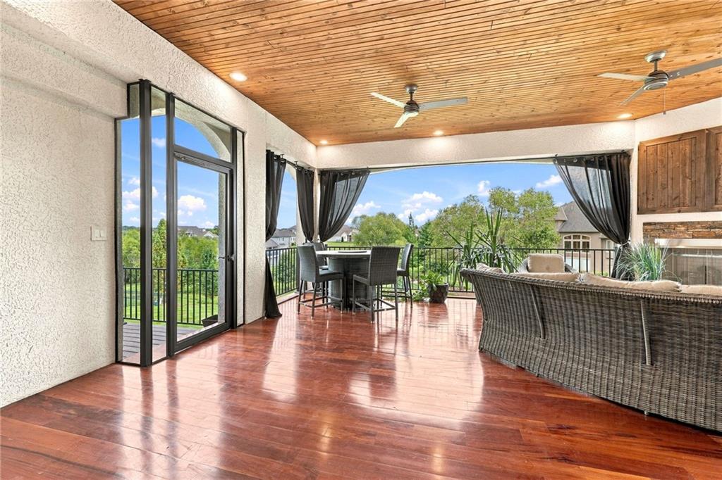 Enclosed patio with wicker seating, a wood-plank ceiling, and views of the green backyard.