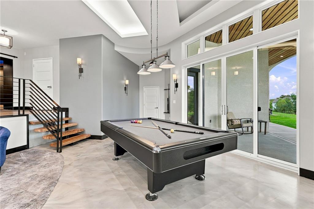Game room with a pool table, open staircase, and large glass doors to a covered patio.