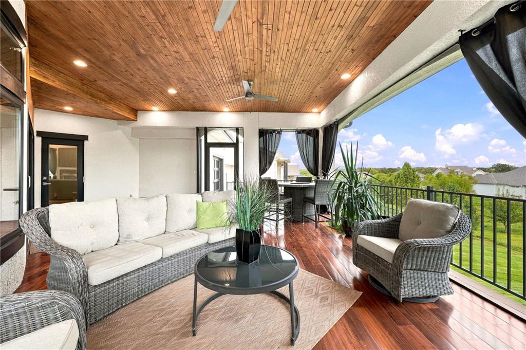 Covered deck with wicker seating, a wood-plank ceiling, and views over green lawns.