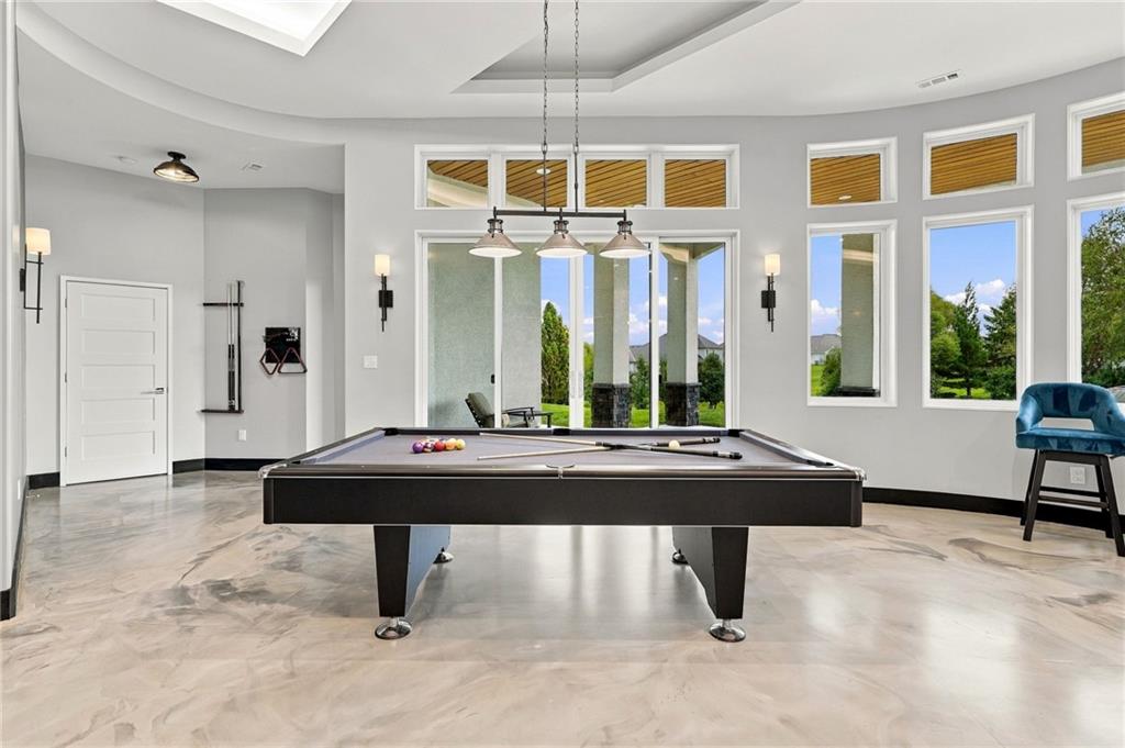 Game room with a billiard table, tall windows, and polished stone flooring.