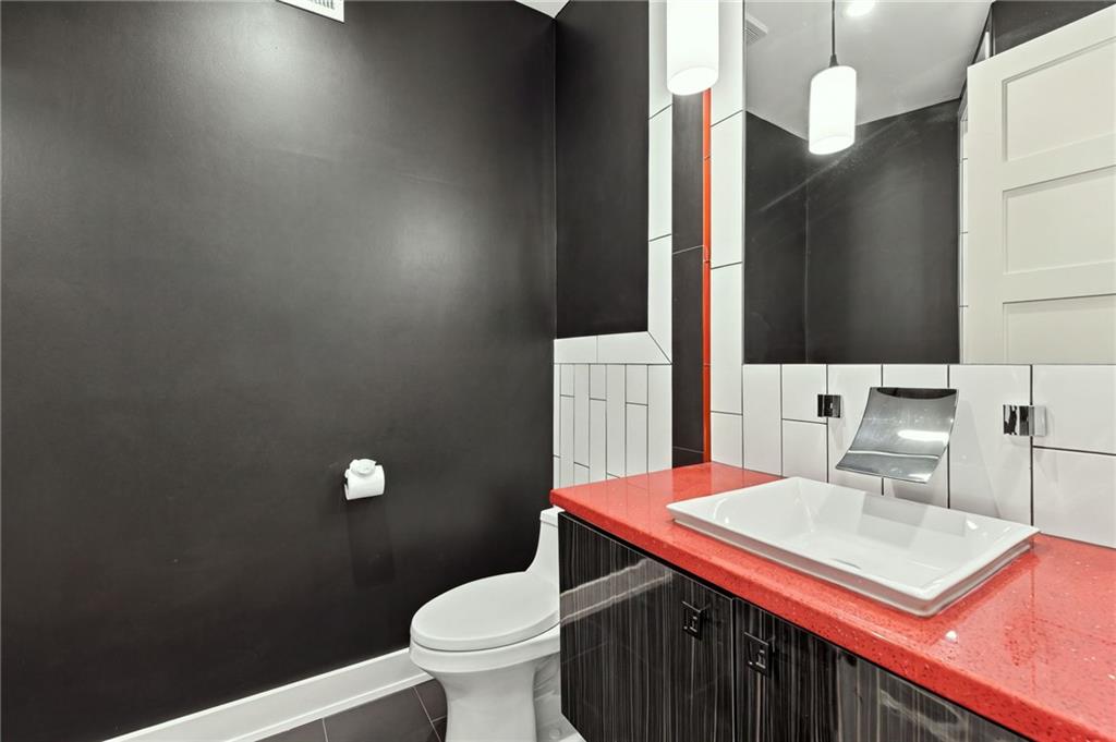 Modern bathroom with a vessel sink on a red countertop and contrasting black walls.