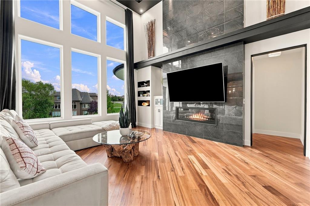 Living room with tall windows, a stone fireplace, and hardwood floors.