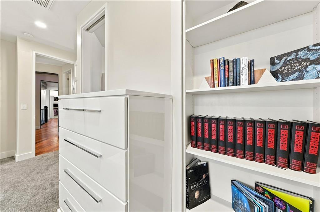 Built-in white drawers and bookshelves filled with books beside a carpeted room doorway.
