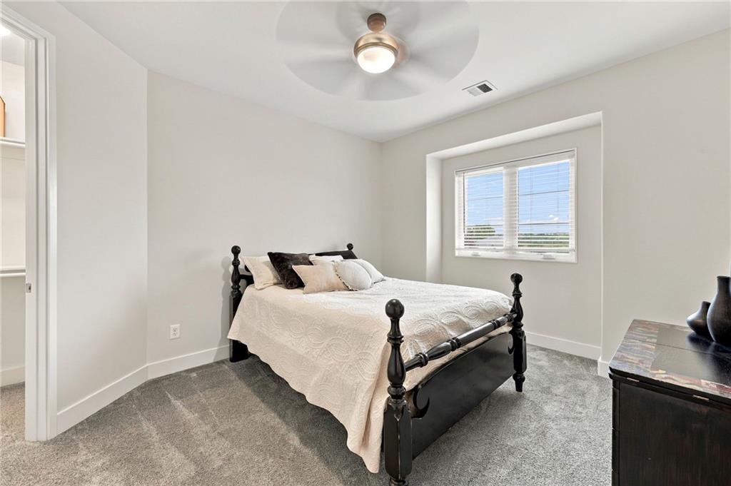 Bedroom with a black four-poster bed, gray carpet, and a window with blinds.