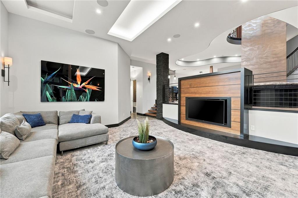 Living room with a gray sectional, round coffee table, and wood-paneled fireplace wall.