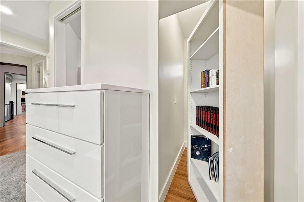 Built-in white drawers and book-filled shelves beside a narrow hallway.