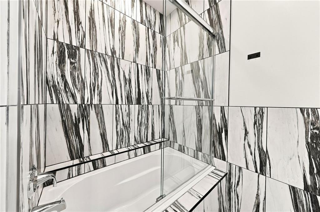 Bathroom with a bathtub, glass shower screen, and dramatic black-and-white marble-pattern tile.