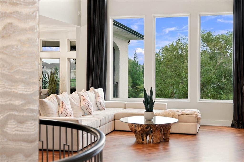 Living room with a cream sectional, tall windows overlooking trees, and a sculptural wood coffee table.