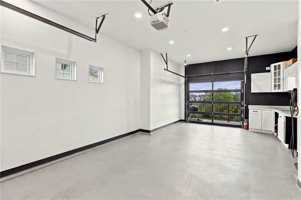 Vacant garage with white cabinets, a gray floor, and a glass-panel overhead door.