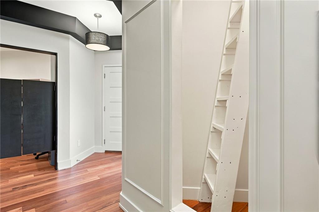 Hallway with hardwood floors, dark double doors, and a built-in shelving unit with a ladder.