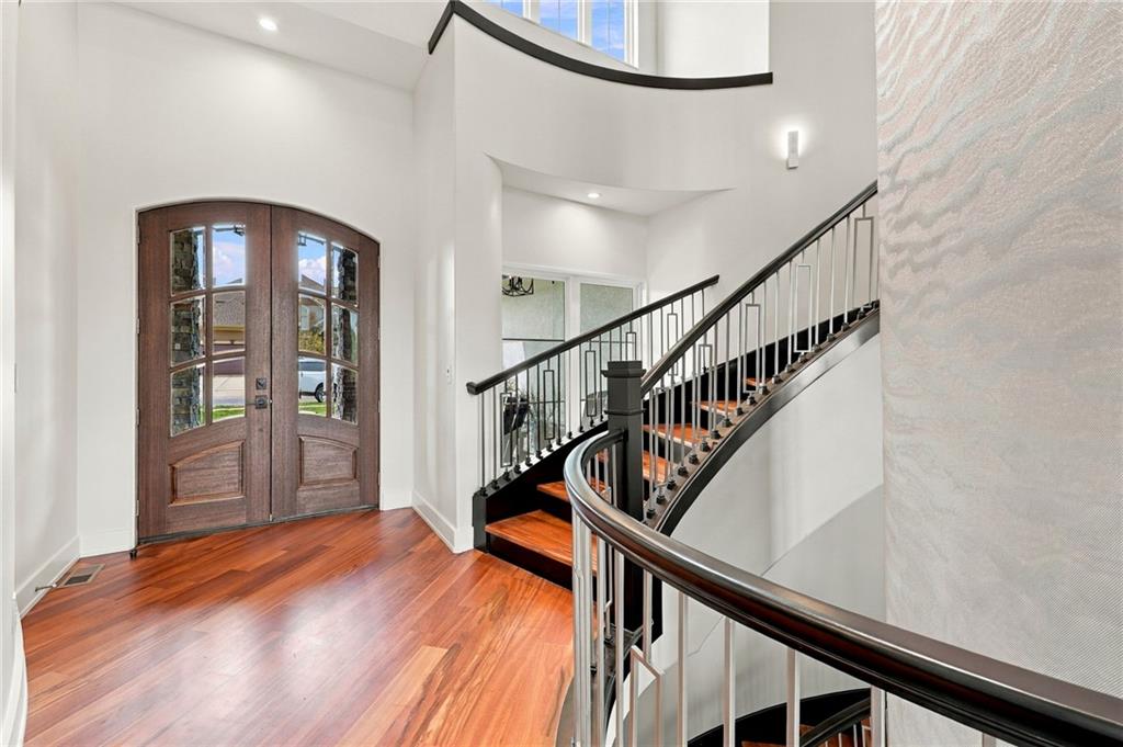 Two-story entry foyer with arched wood-and-glass doors and a sweeping curved staircase.