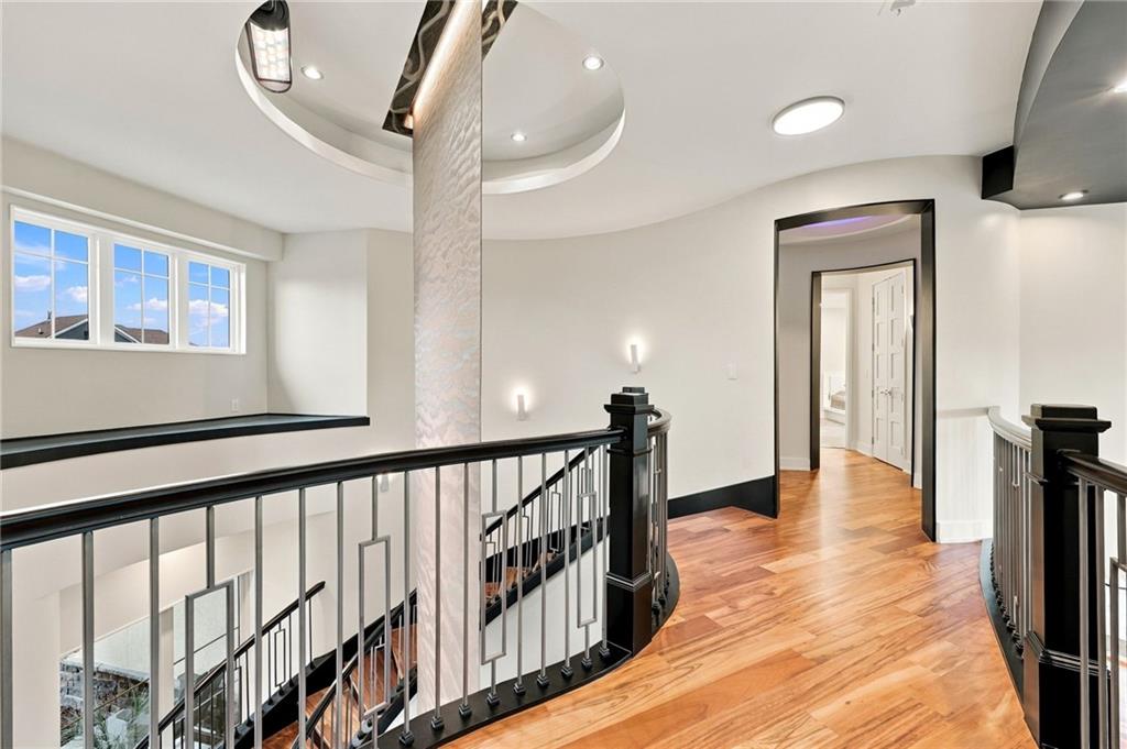 Upstairs landing with polished hardwood floors, black railings, and a curved ceiling feature.