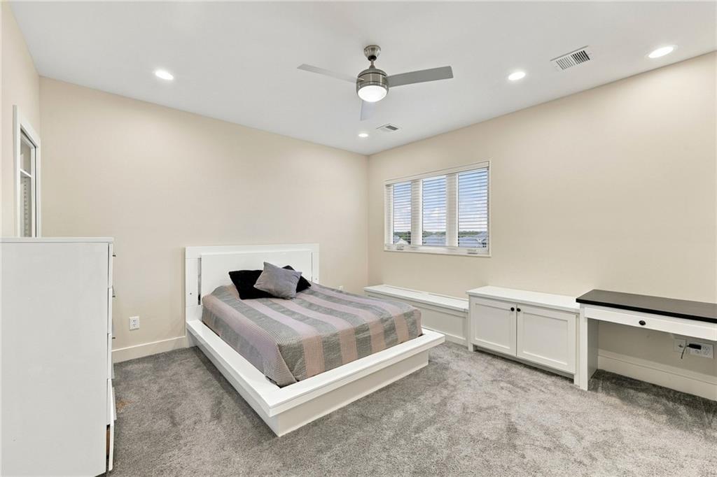 Bedroom with a white platform bed, gray carpet, and built-in cabinets and desk.