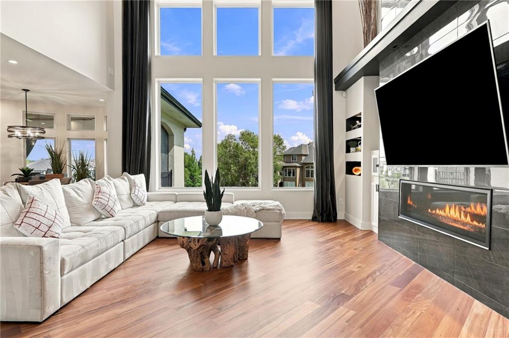 Living room with a white sectional, soaring windows, and a modern fireplace.