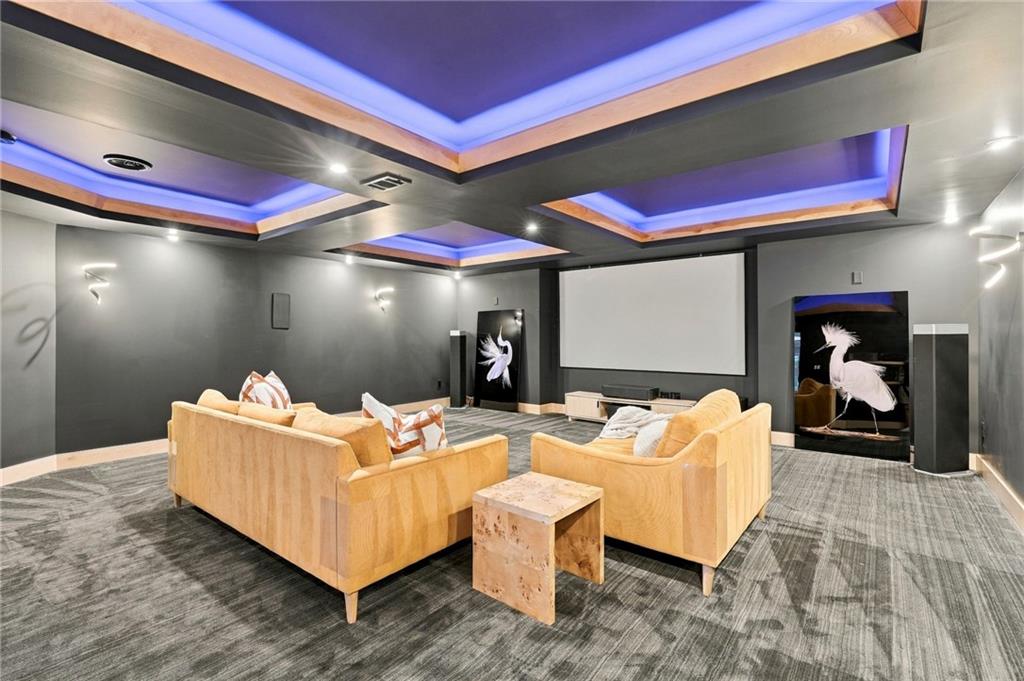 Home theater with tan sofas, a large projection screen, and blue ceiling lighting.