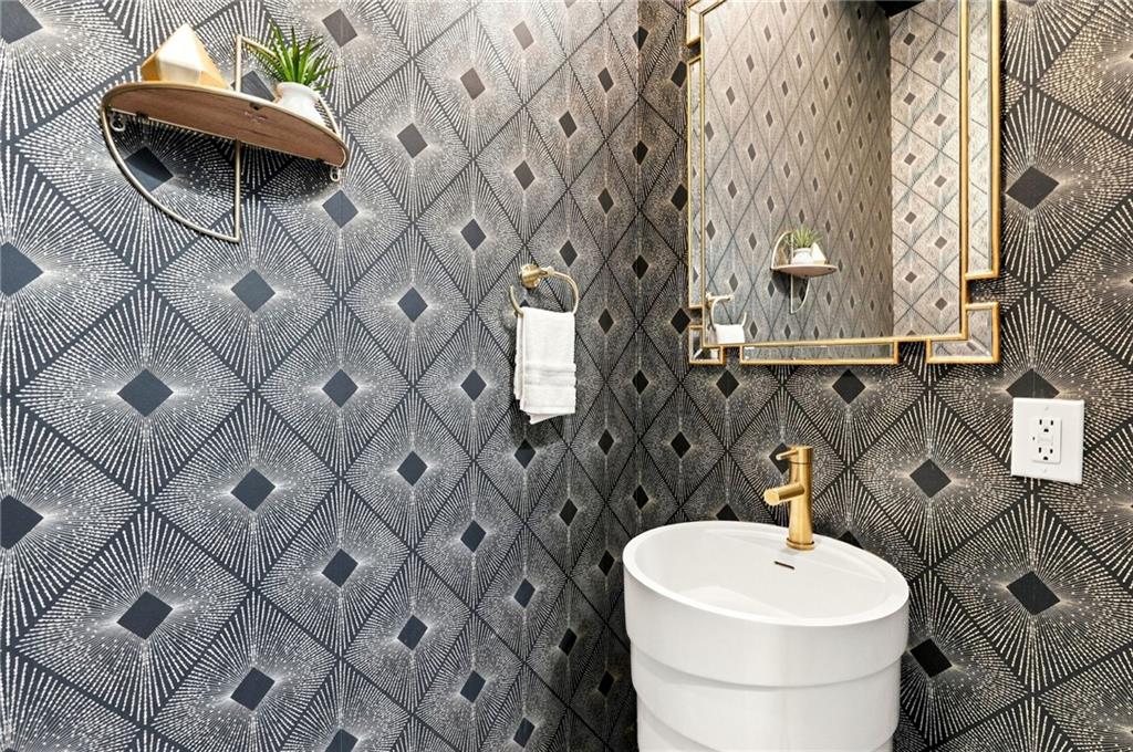 Bathroom vanity with a white vessel sink, gold faucet, and bold geometric tile.