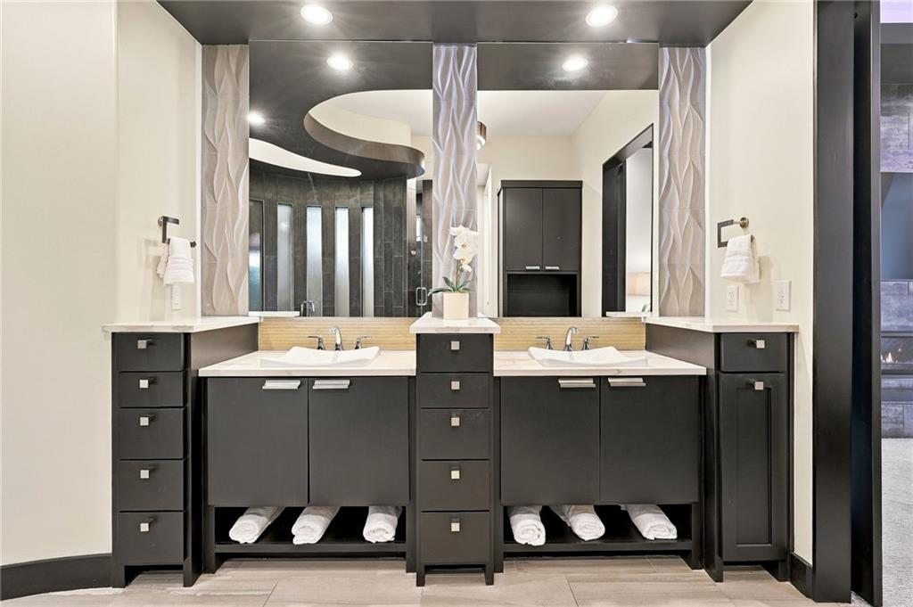 Bathroom with a double vanity, dark cabinets, and a wide mirrored wall.