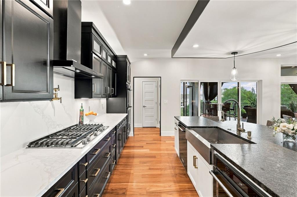 Modern kitchen with dark cabinets, a large island, gas cooktop, and glass doors to an outdoor dining area.