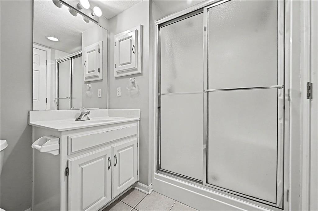 Bathroom with a white vanity, mirrored cabinets, and a sliding frosted-glass shower.