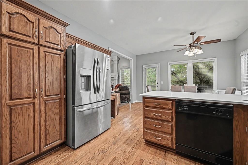 Kitchen with oak cabinets, stainless steel refrigerator, and island with a black dishwasher.