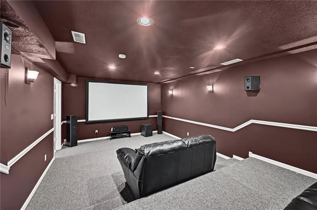 Home theater with a large projection screen, burgundy walls, and a black leather sofa.