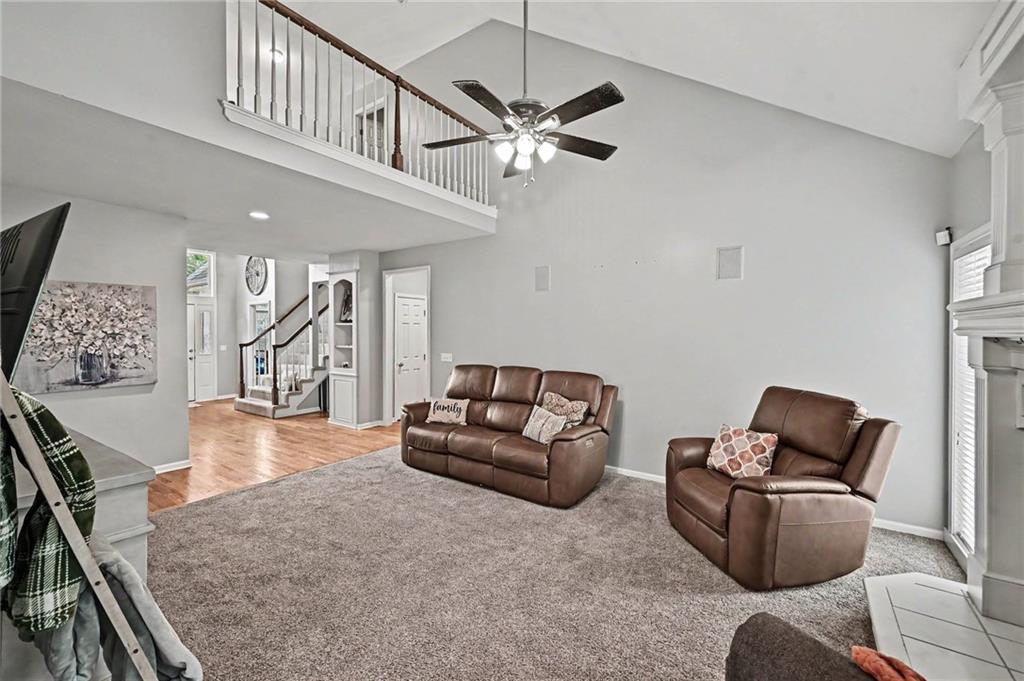 Living room with brown leather seating, gray carpet, and an open loft above.