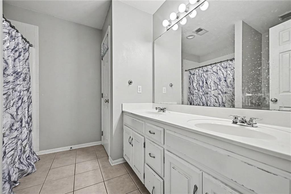 Bathroom with a long double-sink vanity, large mirror, and marble-pattern shower curtain.
