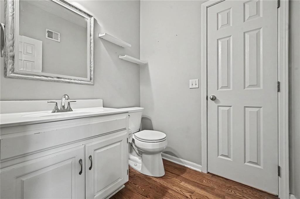 Bathroom with a white vanity and framed mirror beside a toilet and paneled door.