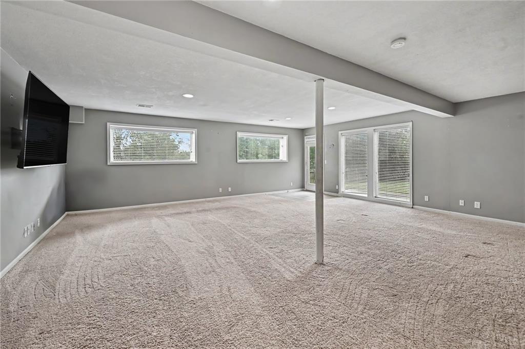 Empty carpeted living area with gray walls, a central support post, and sliding glass doors.