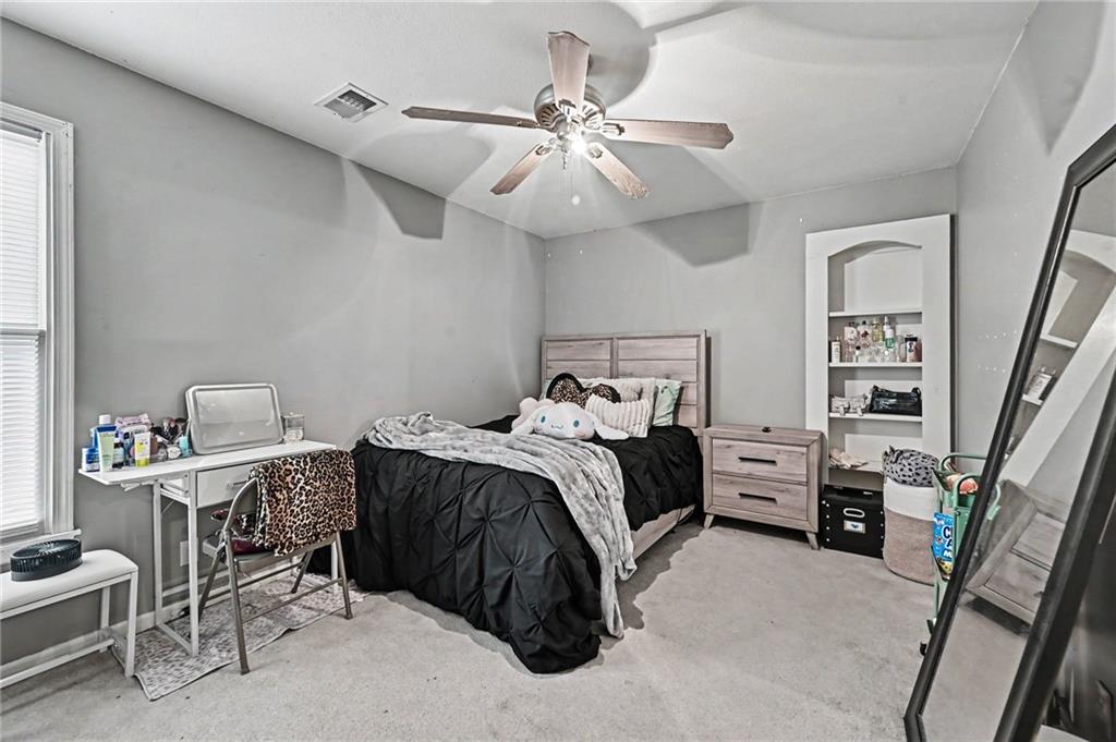Bedroom with black bedding, a ceiling fan, and a desk beside the window.