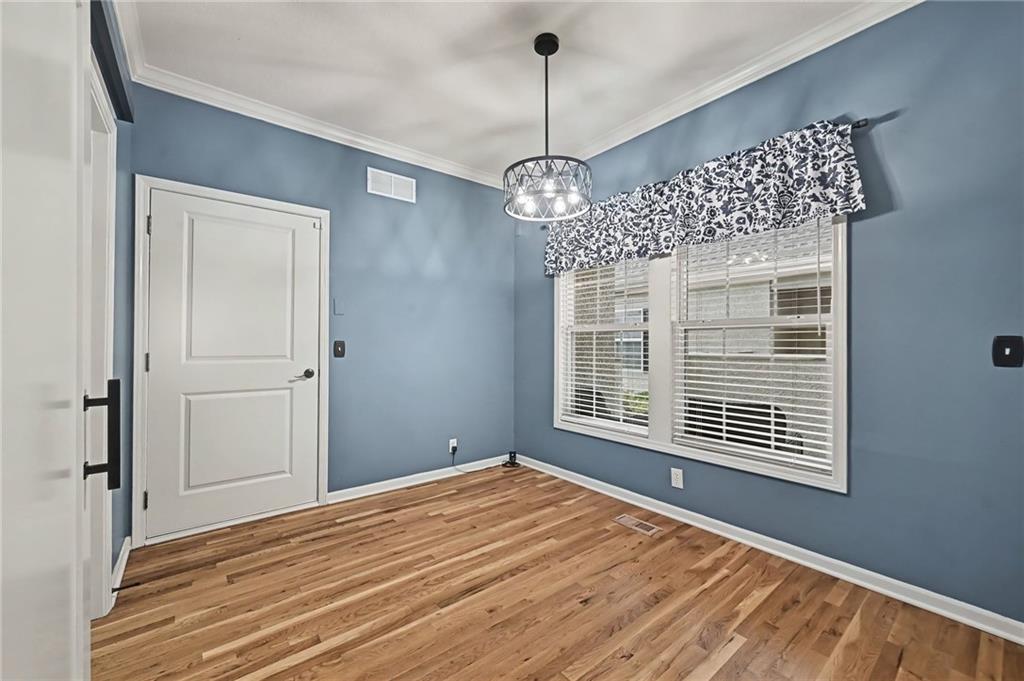 Empty room with blue walls, hardwood floors, a geometric pendant light, and two windows.