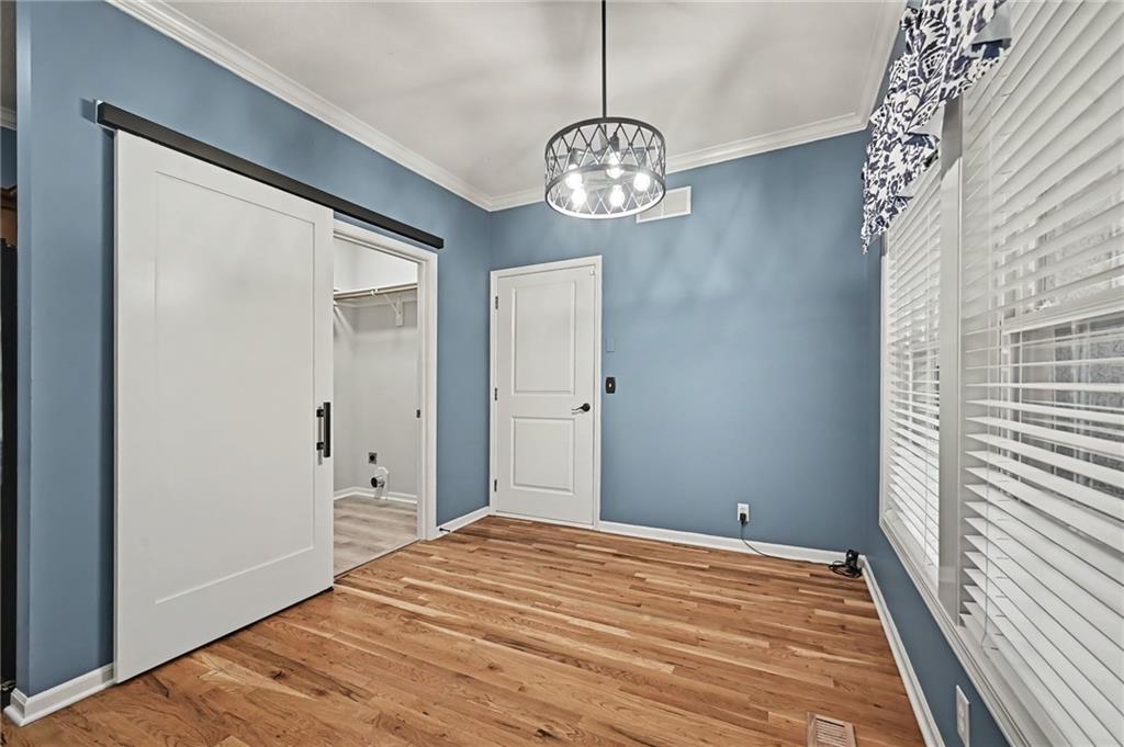 Empty bedroom with blue walls, hardwood floors, an open closet, and large windows with blinds.