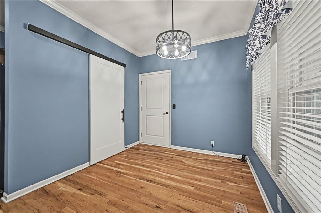 Unfurnished bedroom with blue walls, hardwood floors, and a sliding closet door beside large windows.