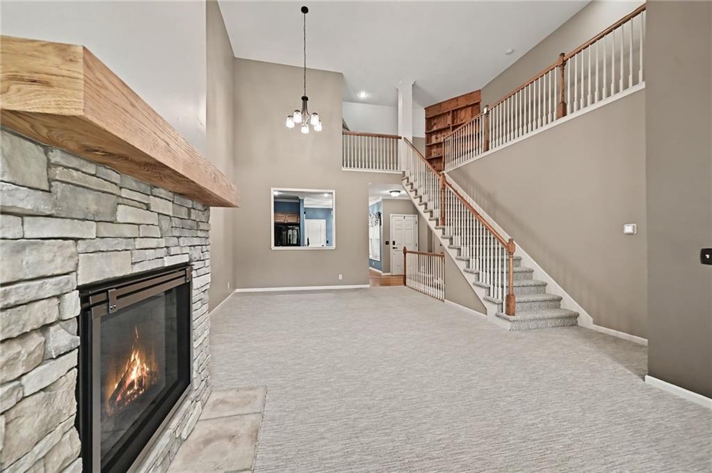 Living room with a stone fireplace and a staircase leading to an upper landing.