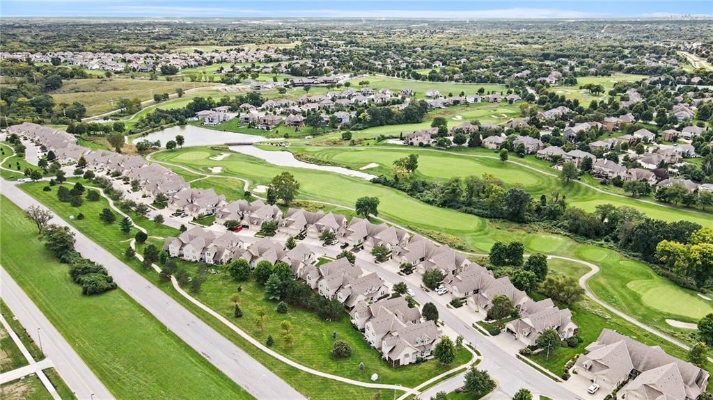 Aerial view of homes beside a golf course with broad green fairways and winding paths.