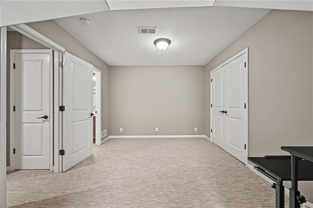 Empty carpeted room with white double closet doors and a ceiling light.