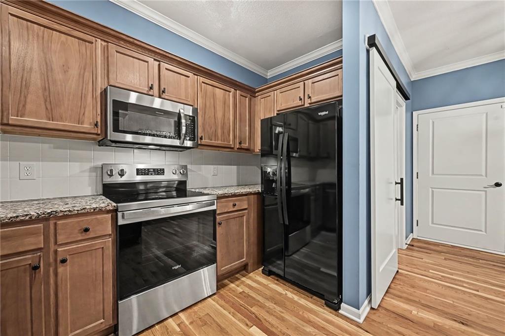 Kitchen with wood cabinets, granite countertops, and stainless steel range beside a black refrigerator.