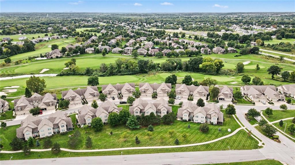 Aerial view of homes beside a golf course with green fairways and sand bunkers.