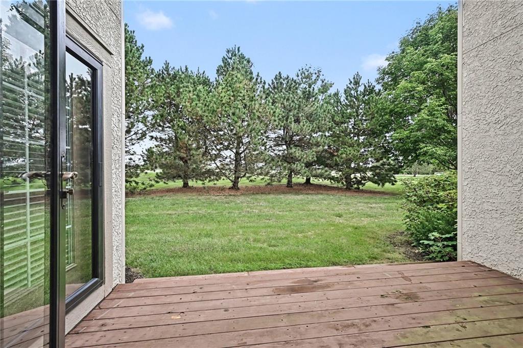 Wooden deck overlooking a grassy backyard bordered by pine trees.