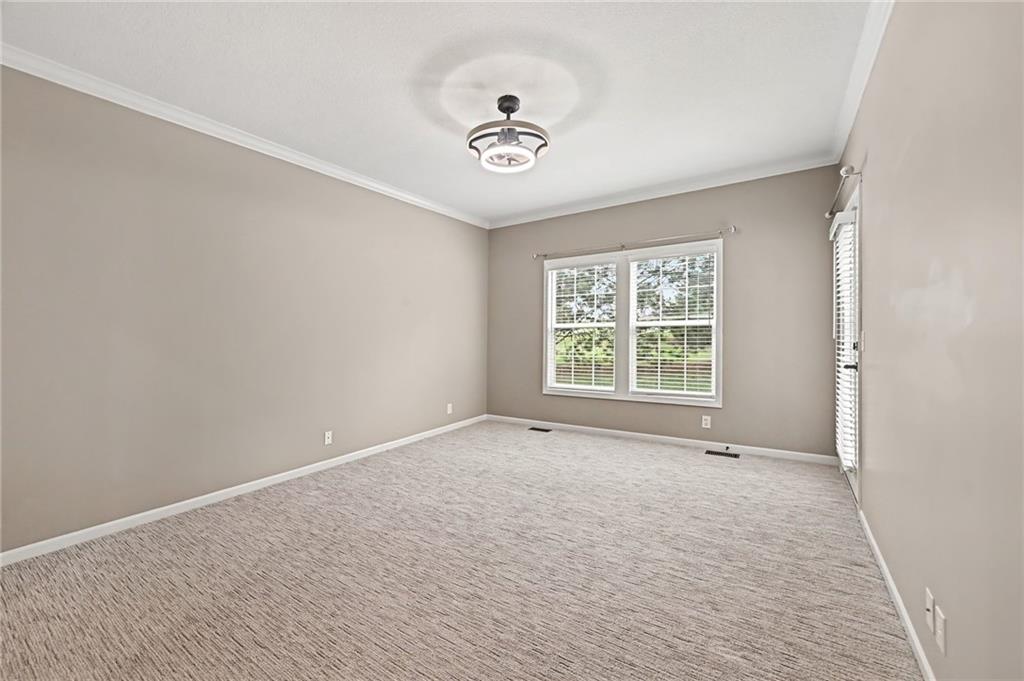 Empty carpeted room with two windows and a ceiling light.