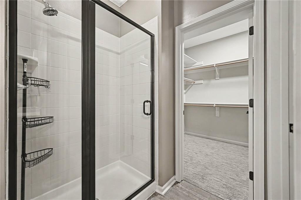 White tiled glass shower beside an open walk-in closet with shelves and hanging rods.