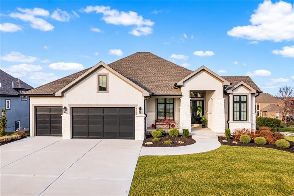 Cream-and-stone home with a three-car garage, curved walkway, and landscaped front lawn.