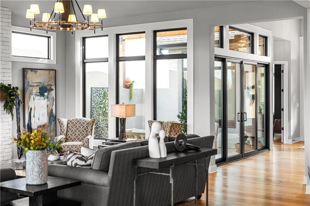 Living room with a gray sofa, white brick fireplace, and tall windows overlooking a patio.