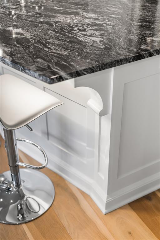 Kitchen island with a dark veined countertop, white paneled base, and chrome bar stool.