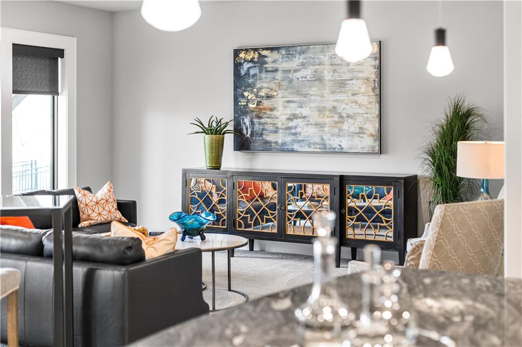 Living room with a black leather sectional and colorful glass-front sideboard beneath abstract artwork.