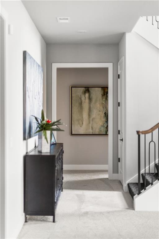 Bright hallway with a dark console table, potted plant, framed art, and staircase.