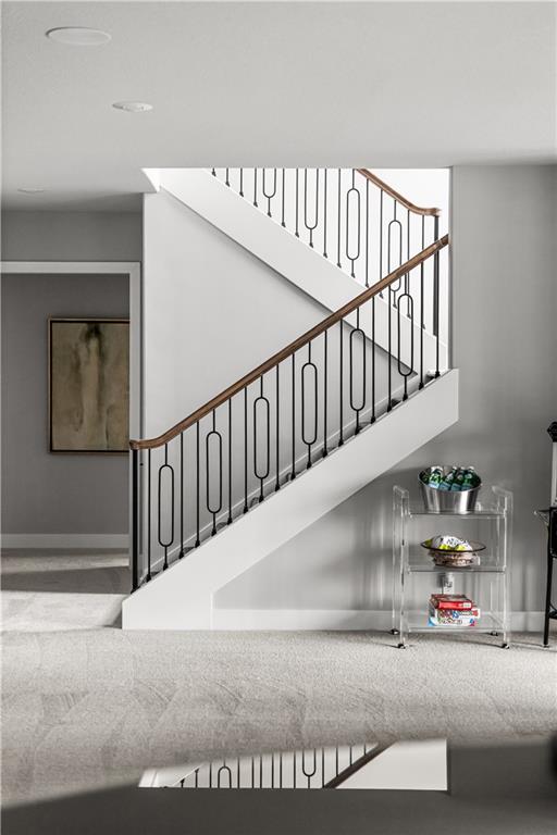Foyer staircase with black metal balusters, a wood handrail, and a clear serving cart.